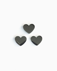 Three heart-shaped stainless steel matcha sifter charms arranged together on a pale grey background